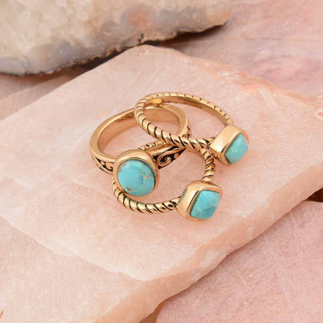 Gold rings with turquoise stones on a stone surface
