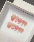 Set of pink and white nail floral y2k art designs with floral details in a white box.