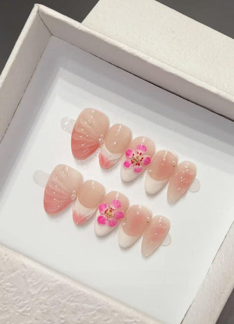 Set of pink and white nail floral y2k art designs with floral details in a white box.