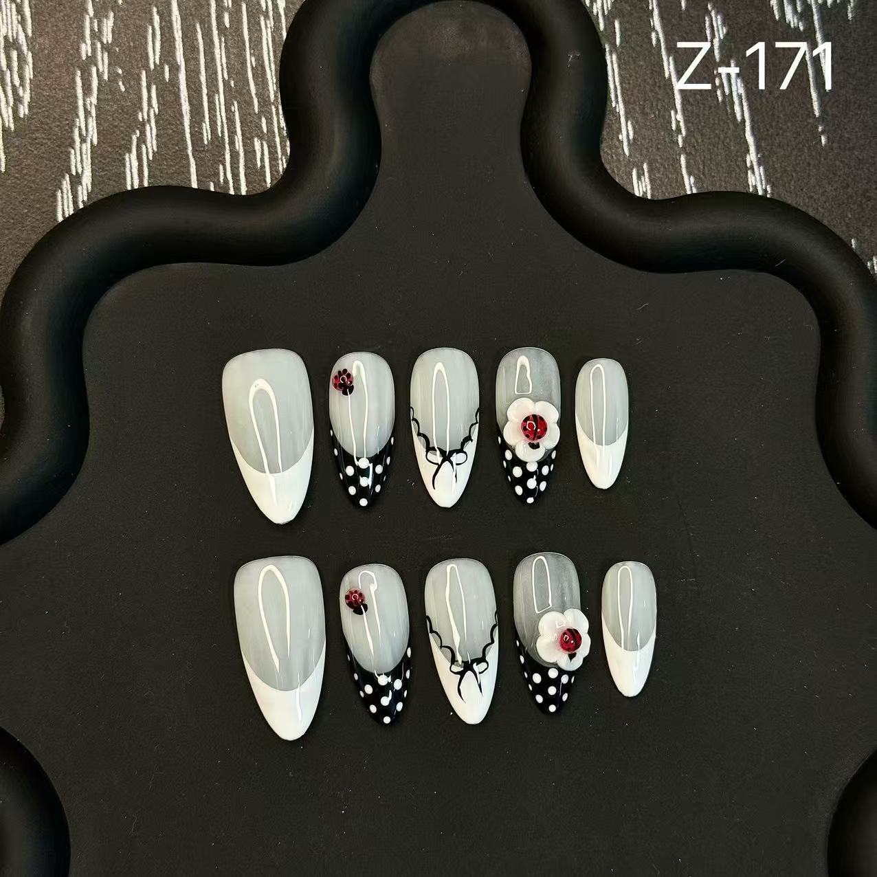 Set of nail art designs on a black stand with a patterned background